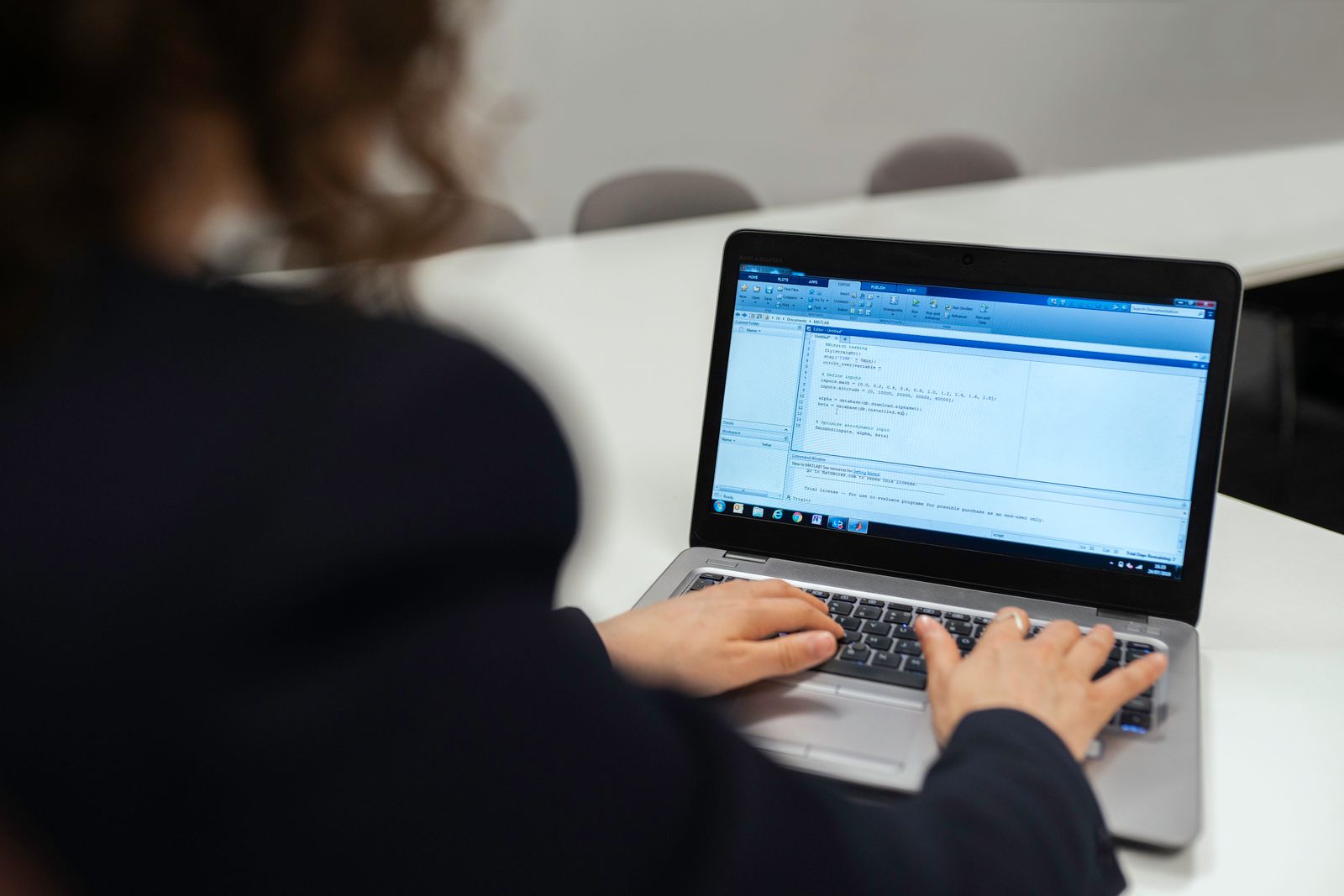Hands resting on an open laptop next to a notebook