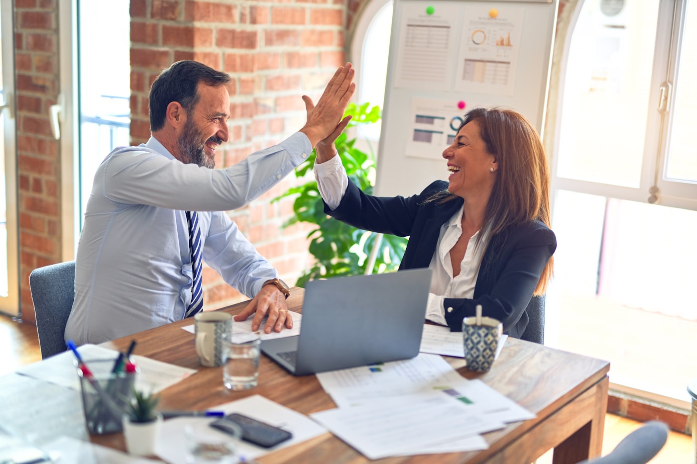 Two colleagues high-fiving to celebrate a partnership