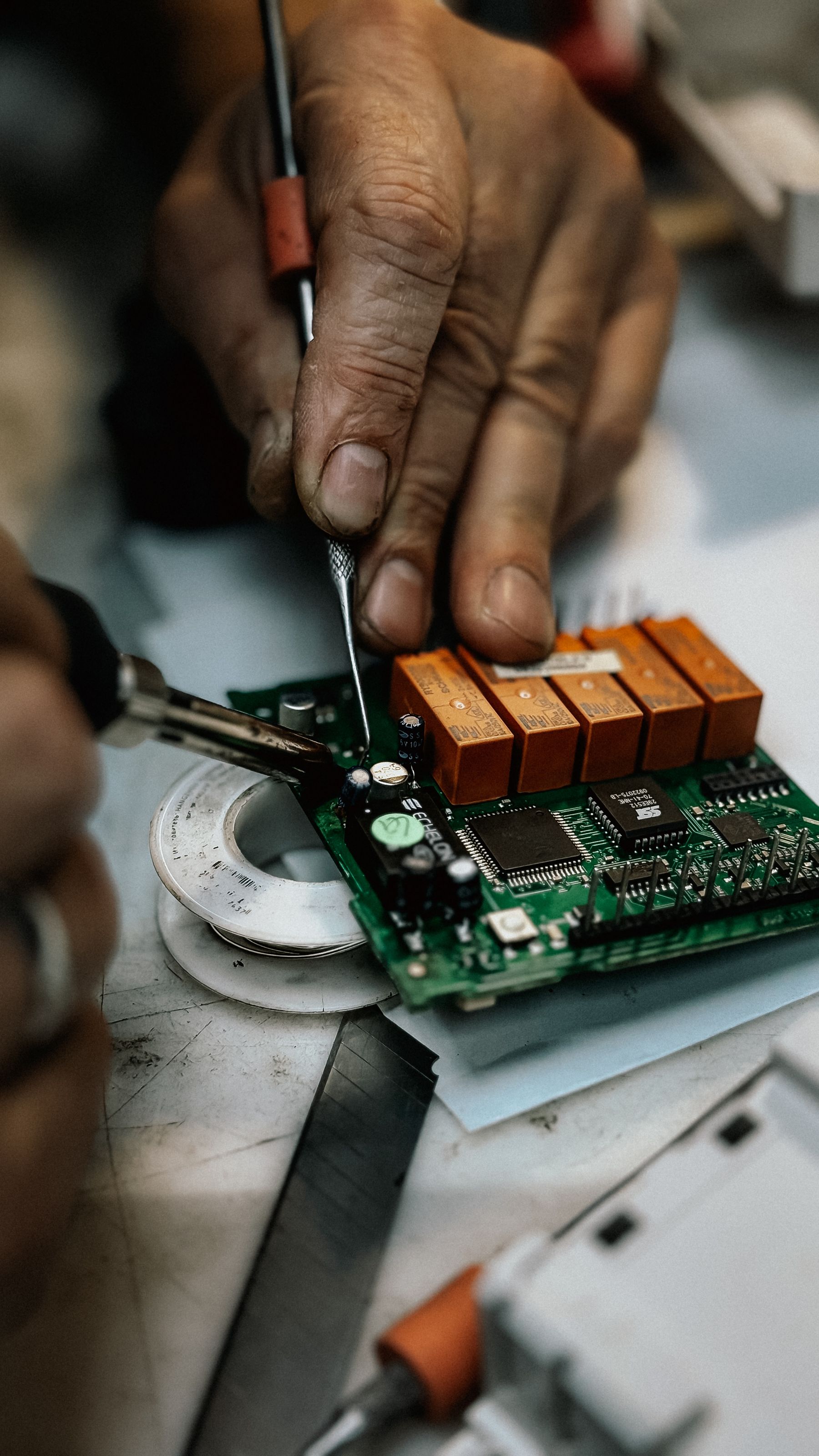 Close-up of a circuit board being repaired with a soldering iron